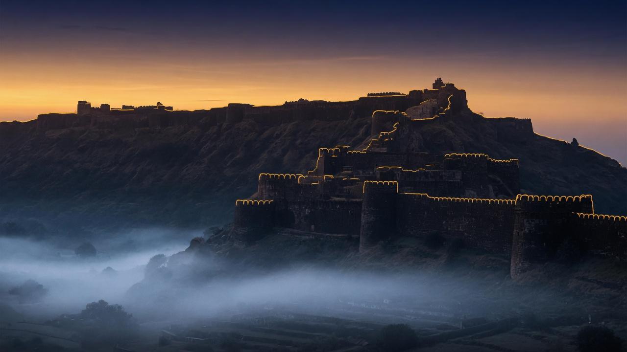 A Deccan mountain fortress at dawn, saffron rim light on dark stone